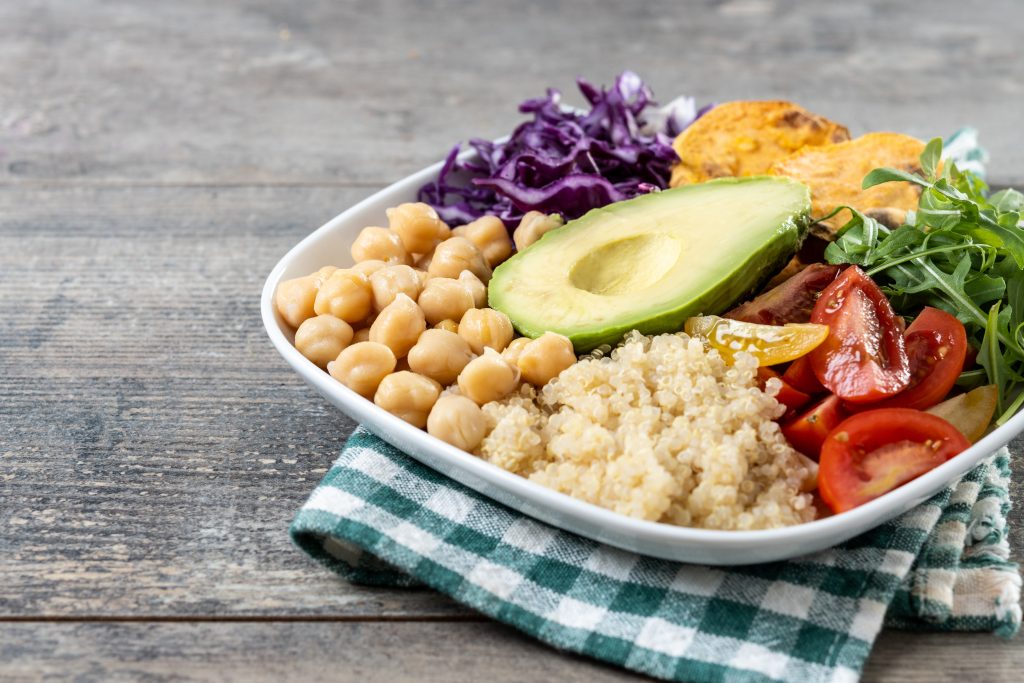 Acerca de Nosotros healthy salad with avocado,lettuce,tomato and chickpeas on white wooden table